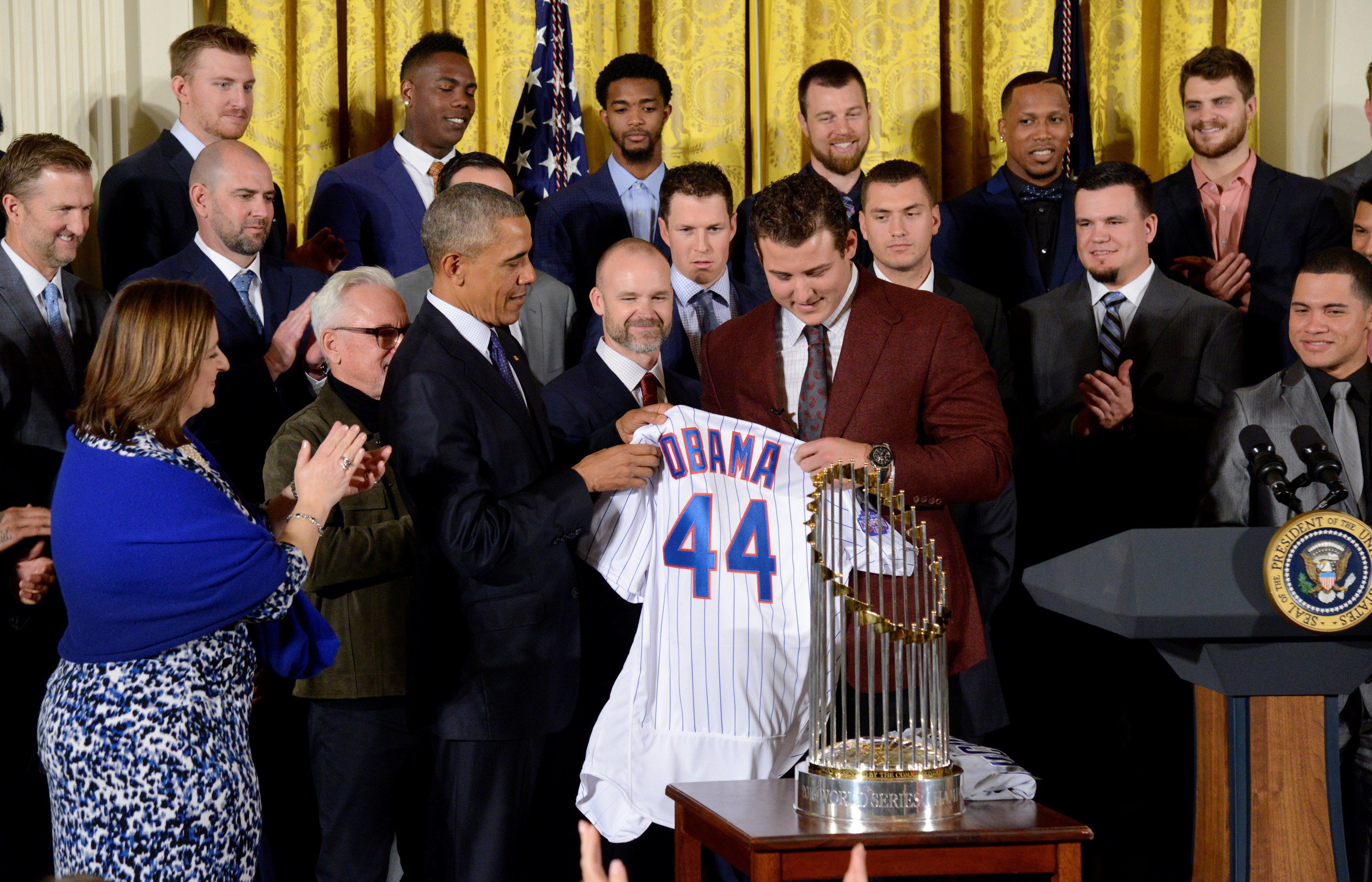 President Barack Obama smiles as Chicago Cubs first baseman Anthony Rizzo  presents him with a 'Chicago' jersey during a ceremony to honor the Cubs in  the East Room of the White House