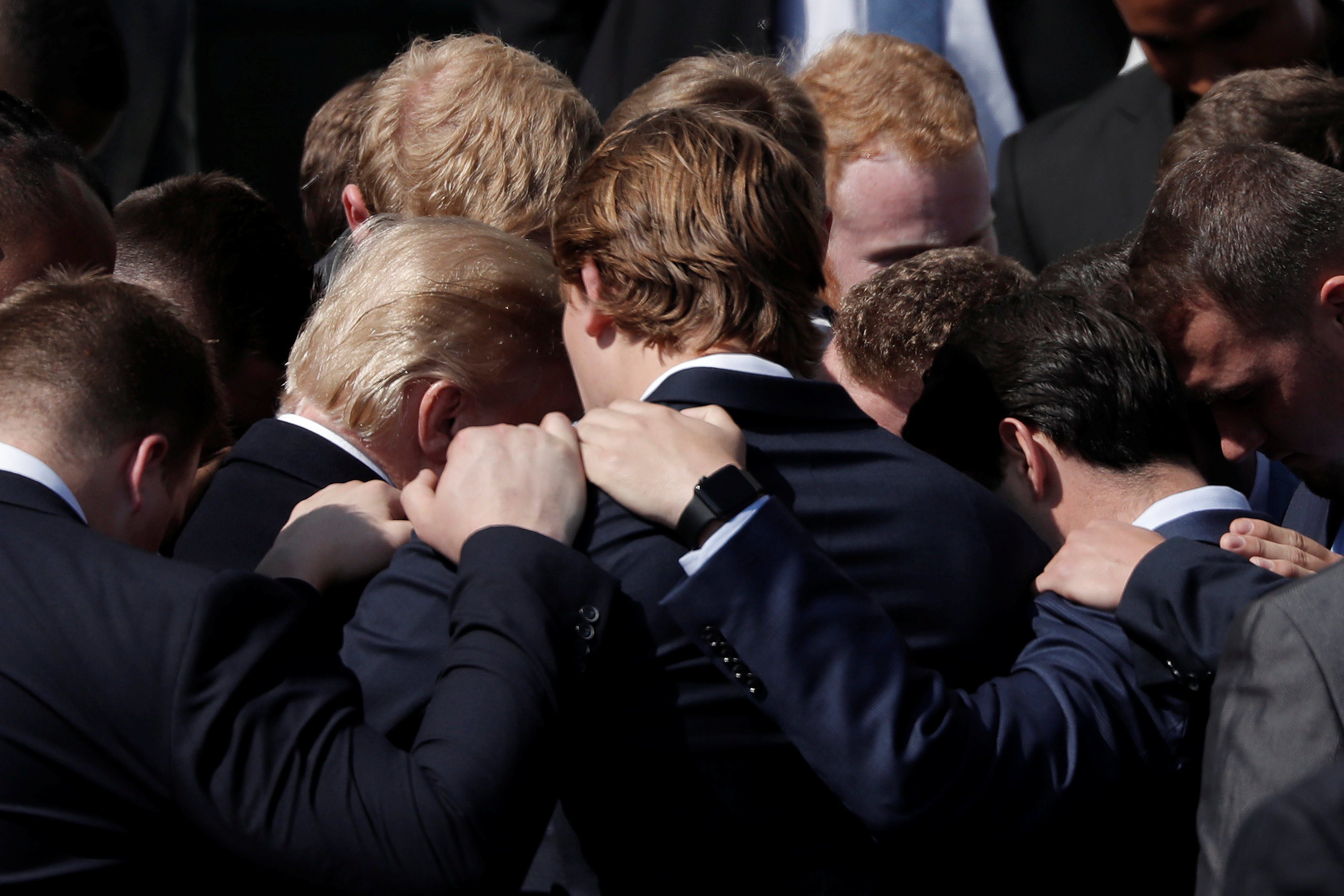 U.S. President Donald Trump prays with team members of the 2017 NCAA Football National Champions, The Alabama Crimson Tide during an event hosted at the South Lawn of the White House in Washington