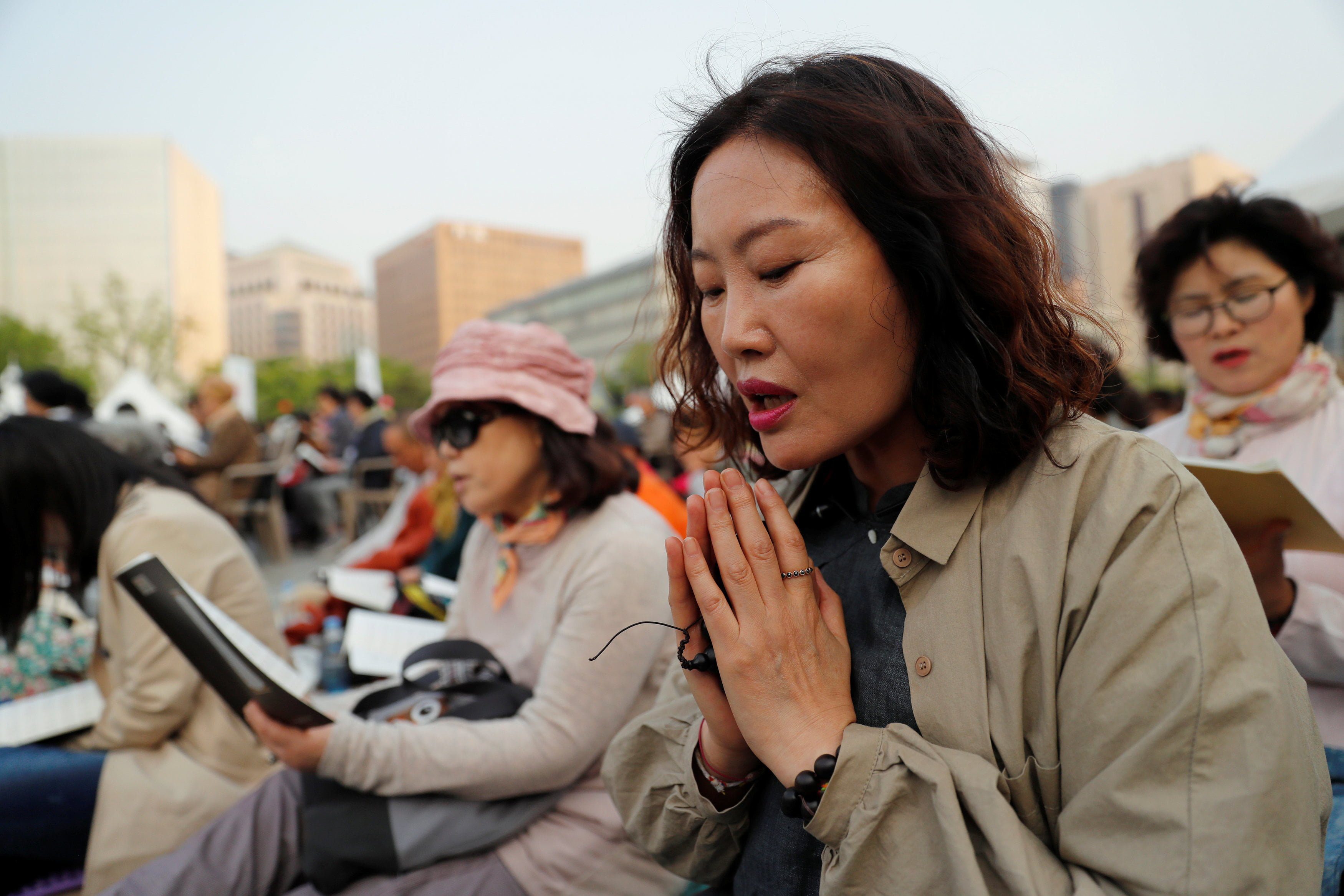 A Buddhist woman clasps her hands together during a prayer service wishing for a successful inter-Korean summit in Seoul, South Korea