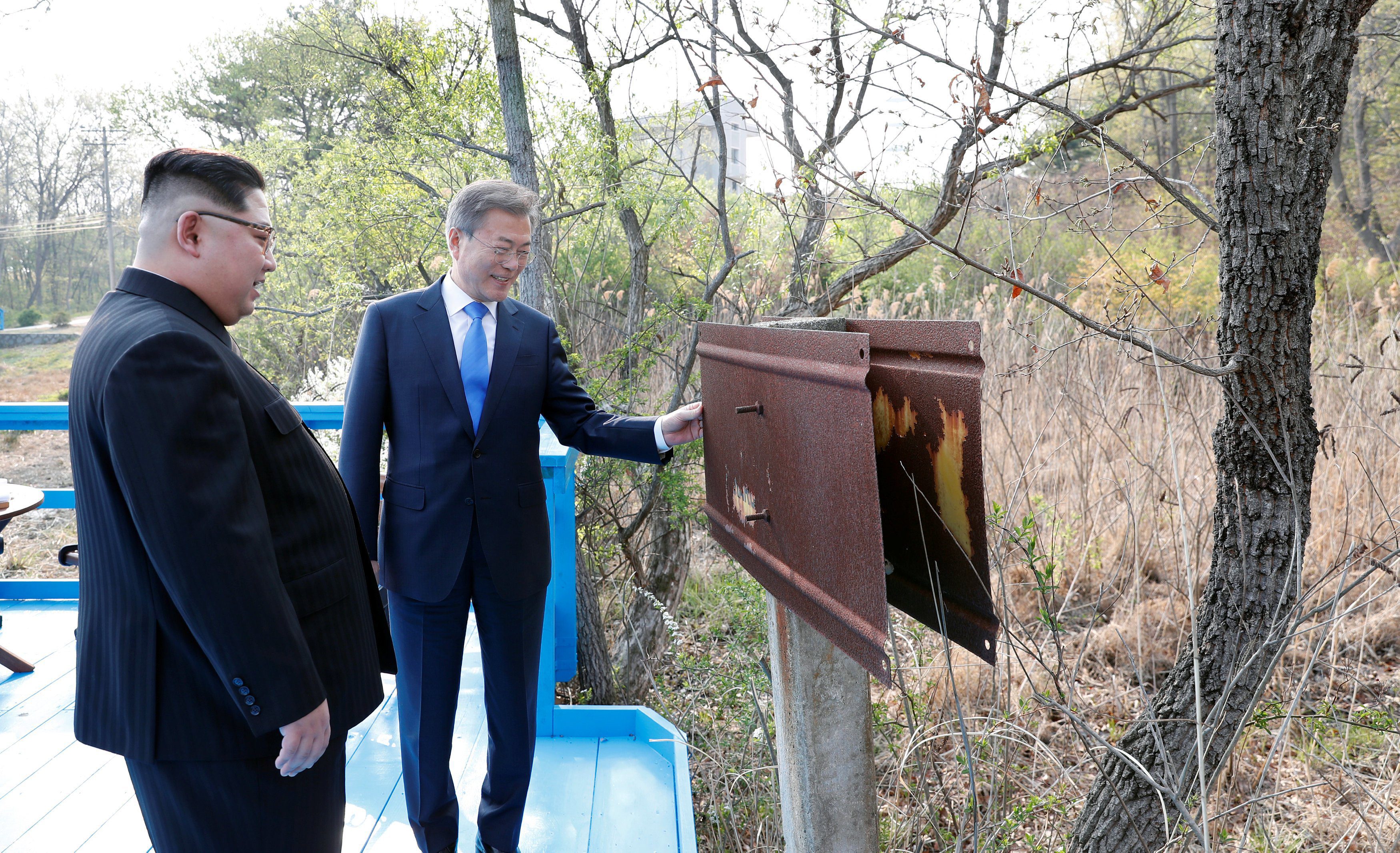 South Korean President Moon Jae-in and North Korean leader Kim Jong Un examine a rusted sign at the demarcation line at the truce village of Panmunjom