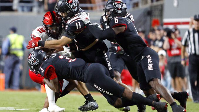 Texas Tech's Tahj Brooks (28) is tackled by North Carolina State's Aydan White (3), Payton Wilson (11), and Jakeen Harris (6) during the second half of an NCAA college football game in Raleigh, N.C., Saturday, Sept. 17, 2022.